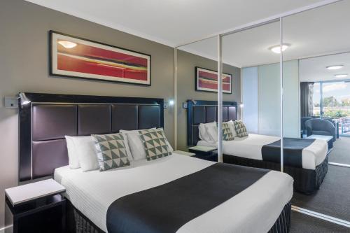 a hotel room with two beds and a balcony at Nesuto The Entrance in The Entrance