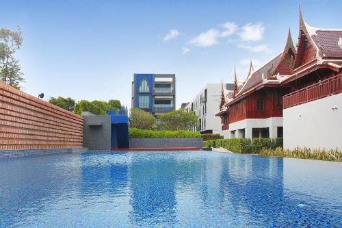 a swimming pool with blue water in front of buildings at Aksorn Rayong, The Vitality Collection - SHA PLUS in Klaeng