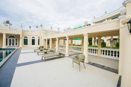 un gran edificio blanco con sillas y piscina en Kensington English Garden Resort Khaoyai, en Wangkata