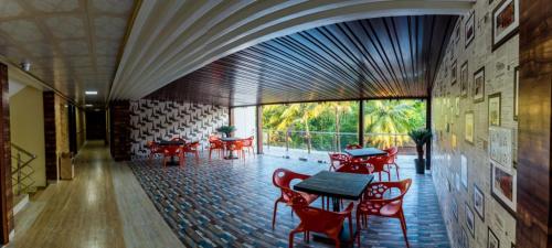 a restaurant with red chairs and tables in a room at Hotel Grace Majestic in Madgaon