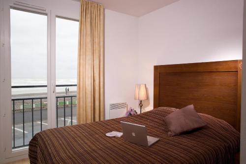 een slaapkamer met een bed met een laptop erop bij Madame Vacances Les Terrasses De La Plage in Cayeux-sur-Mer