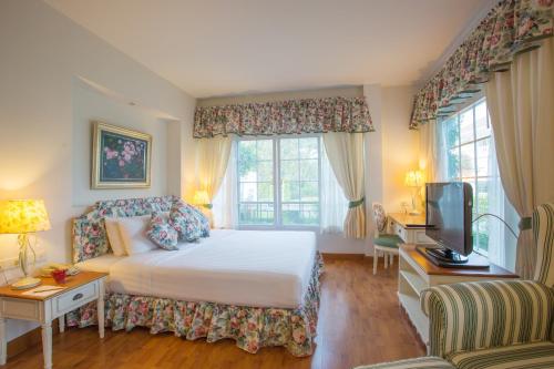 una camera con letto, TV e finestre di Kensington English Garden Resort Khaoyai a Wangkata