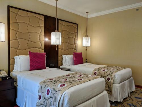 two beds in a hotel room with pink pillows at Taj Krishna in Hyderabad