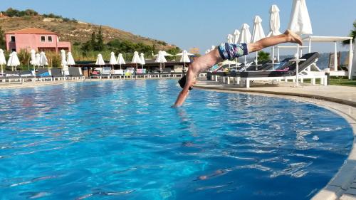a man is diving into a swimming pool at Kiani Beach Resort Family All Inclusive in Kalyves