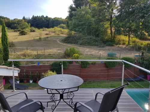 een patio met een tafel en stoelen en een zwembad bij Les Bruyères in Civrieux-dʼAzergues