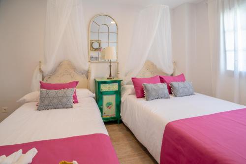 2 camas en una habitación de color rosa y blanco en A&S Apartamentos Malaga, en Málaga