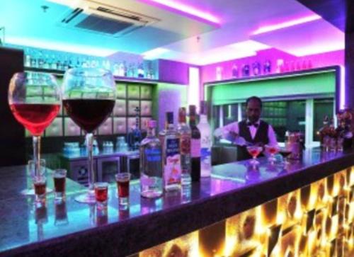 a man standing behind a bar with two glasses of wine at Brijwasi Lands Inn in Mathura