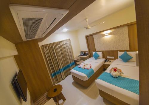 a hotel room with two beds and a television at Hotel iStay in Coimbatore