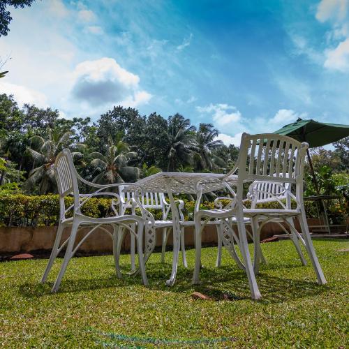 two white chairs and a table and an umbrella at Gurubeula Leisure As You Wish in Deniyaya