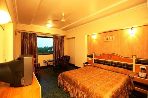 a hotel room with a bed and a flat screen tv at Brijwasi Royal in Mathura
