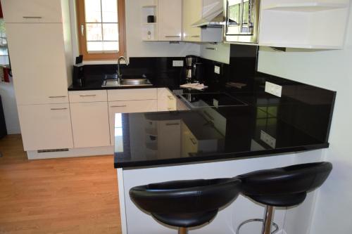 a kitchen with black counter tops and black stools at A Casa Residenz in Sölden