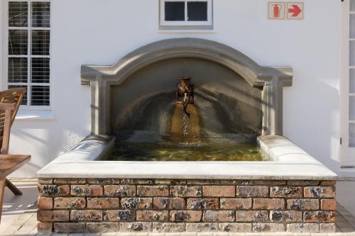 a water fountain in the middle of a brick fireplace at Constantia White Lodge Guest House in Cape Town