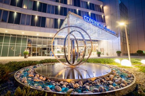 a fountain in front of a building at night at Copernicus Toruń Hotel in Toruń