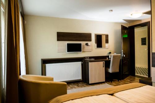una camera d'albergo con letto e scrivania con TV di Domino Residence a Zimandcuz