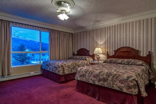 Habitación de hotel con 2 camas y ventana grande. en Athabasca Hotel en Jasper