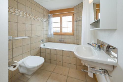 a bathroom with a toilet and a sink and a tub at Beatrice in Grächen