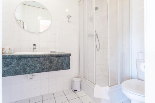 een badkamer met een douche, een wastafel en een toilet bij Avenue Hotel by F-Hotels in Blankenberge