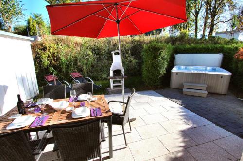 a wooden table with a red umbrella on a patio at Ferienhaus GOLFER_S HOUSE in Göhren-Lebbin