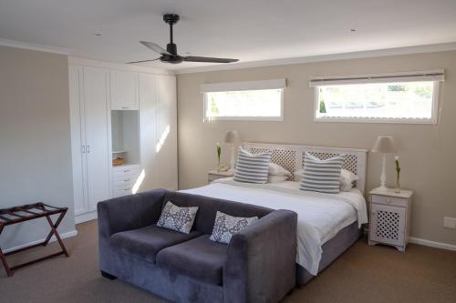 a bedroom with a bed and a couch and windows at Constantia White Lodge Guest House in Cape Town