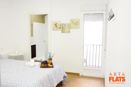 a white bedroom with a bed and a window at Calle Cuenca in Valencia