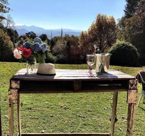 a wooden table with two wine glasses and flowers on it at Hawley House in Underberg