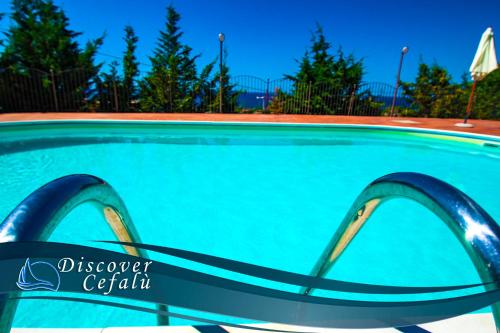 een zwembad met blauw water en bomen bij Residence Villa Santa Lucia in Cefalù