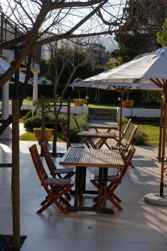 a group of tables and chairs with an umbrella at Constantia White Lodge Guest House in Cape Town