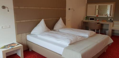 a bedroom with a white bed with pillows on it at Confour Hotel in Burgdorf
