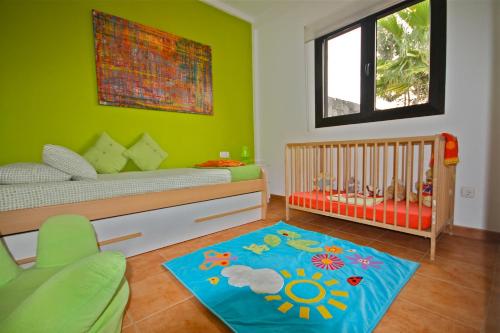 Dormitorio infantil con cuna y pared verde en Villa Arianne, en Playa Blanca