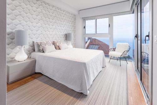 a white bedroom with a bed and a chair at SuperMakar10 - Green Palm in Santa Úrsula