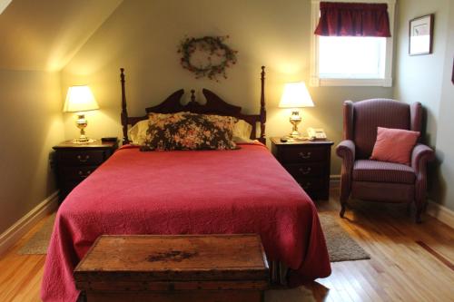 a bedroom with a red bed and a chair at Ye Olde Argyler Lodge in Pubnico