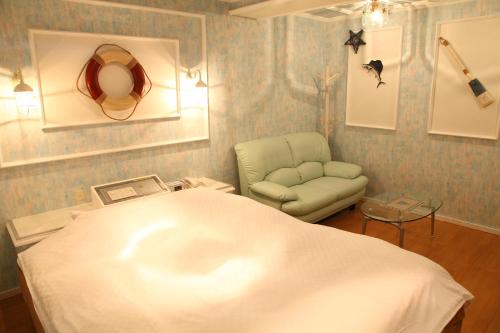 een ziekenhuiskamer met een bed en een stoel bij Ciao-LoveHotel in Miyazaki