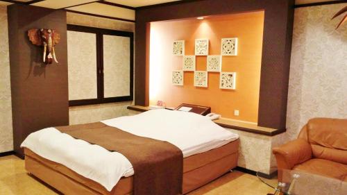 een slaapkamer met een groot bed en een stoel bij Ciao-LoveHotel in Miyazaki