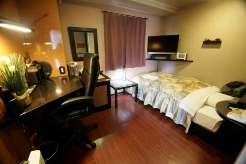 a hotel room with a bed and a desk with a computer at Hotel Satellite in Satsumasendai