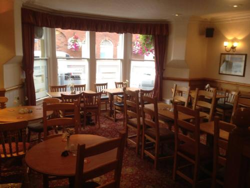 a dining room with tables and chairs and windows at The Wellington Hotel in Howden