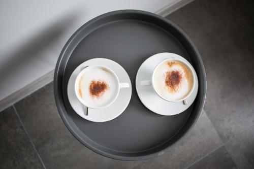 two cups of coffee on a black plate at Hotel Greys Polonia in Zasutowo