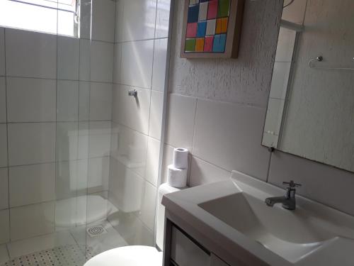 a bathroom with a sink and a toilet and a mirror at Pousada Solar dos Cavaleiros Mendes in Macaé