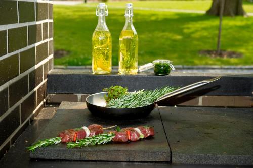 a grill with meat and vegetables and two bottles of oil at Hotel Panství Dlouhá Lhota in Dlouhá Lhota