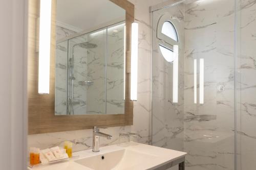 Un baño con lavabo, espejo y ducha. en Petit Palace Triball, en Madrid