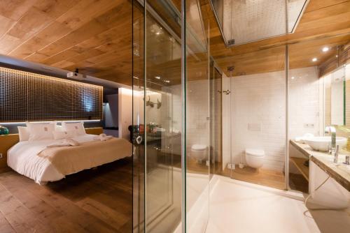 テラサにあるPetit Luxe Loftのベッドルーム1室(ベッド1台、ガラス張りのシャワー付)