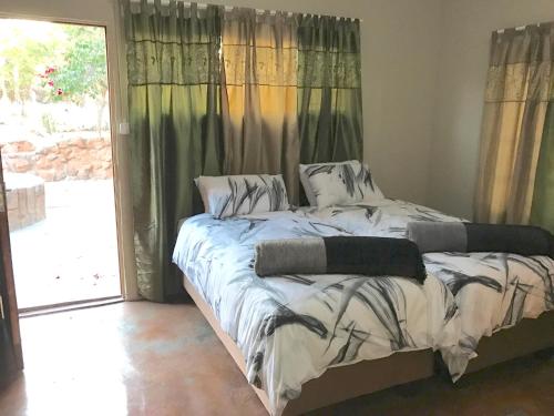 a bed in a room with a large window at Klein Paradys Lodge - Polokwane in Polokwane