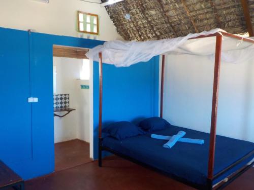 a bedroom with a blue bed with a canopy at SANJEELA-PLAGE COCO in Antsiranana