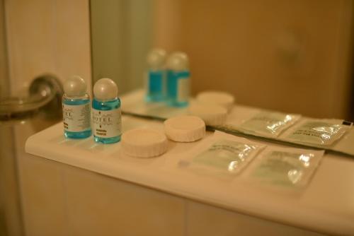 a bathroom counter with bottles ofodorizers and a mirror at Foton Hotel & Restaurant in Ochakiv