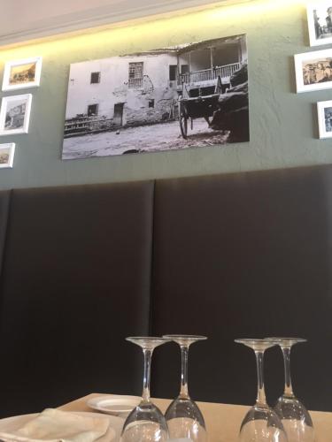 three wine glasses on a table with a picture on the wall at Hotel Resort Cueva del Fraile in Cuenca
