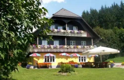 a yellow house with a balcony with flowers on it at Raffelwirt in Deutschgriffen