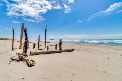 a beach with a bunch of logs on the sand at 4th Avenue Beach Cottage in Rockaway Beach