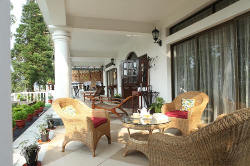 a patio with wicker chairs and a table on a porch at Sourenee Tea Estate in Mirik