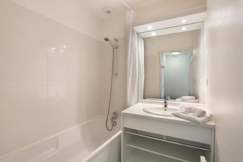 La salle de bains blanche est pourvue d'un lavabo et d'une douche. dans l'établissement Résidence Néméa Iroise Armorique, à Loc-Maria-Plouzané