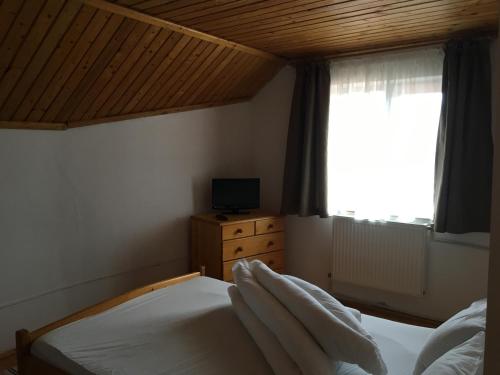 a bedroom with a bed with white sheets and a window at Vila Carla Elena Ranca in Ranca