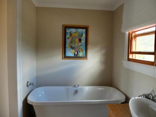a bathroom with a white tub and a painting on the wall at Doorways in Barrydale